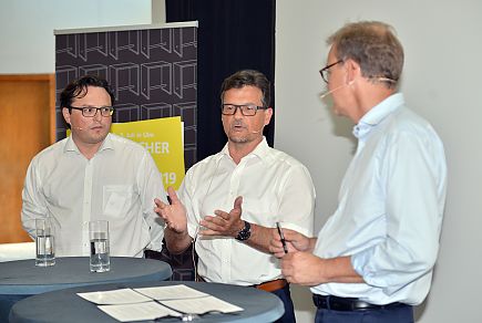 Dominik Metzler (PASSAVIA Druckservice) und Oliver Machhold (Wahl-Druck) mit Moderator Holger Busch (VDMB)